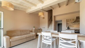 Un intérieur moderne comprenant un canapé, une table à manger, des chaises et un escalier.