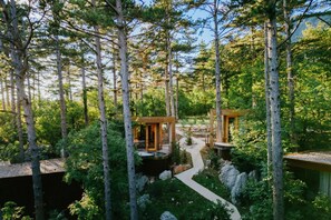 Une zone boisée comprenant deux cabanes en bois reliées par un sentier.