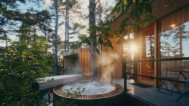 A hot tub surrounded by a wooden deck, with a glass enclosure and a bench. - Theodosius Glamping Mobile Home (Vipava)