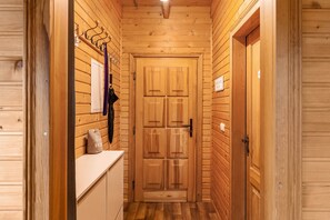 Un corridoio in legno con una porta doppia, un appendiabiti e una piccola panca con cuscino.