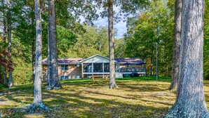 A two-story house with a porch, surrounded by trees. - Lakefront Home with Private Dock, Hot Tub, Fireplace, & Central A/C - Free WiFi (Bumpass)
