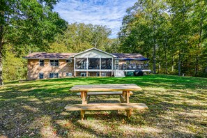 A two-story house with a covered porch, a picnic table in the front yard, and a lawn.