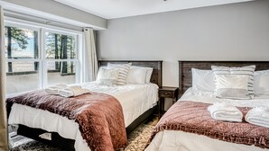 A bedroom with two beds, a ceiling fan, and a view of the outdoors through large windows. - Lakefront Home with Private Dock, Hot Tub, Fireplace, & Central A/C - Free WiFi (Bumpass)