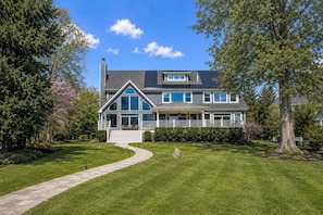 A two-story house with a covered porch, a stone pathway, and a well-maintained lawn.
