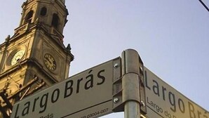 Señal de calle para Largo do Brás con una torre del reloj al fondo.