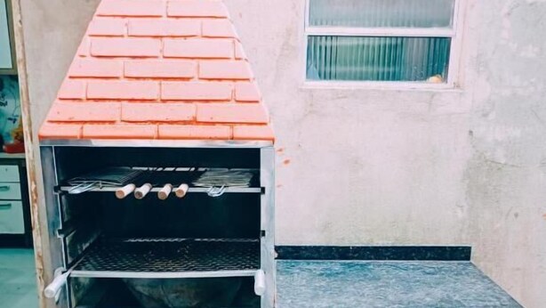 Un horno exterior de ladrillo con varios estantes y una chimenea.
