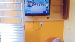 Un televisor montado en la pared con un estante de madera debajo.
