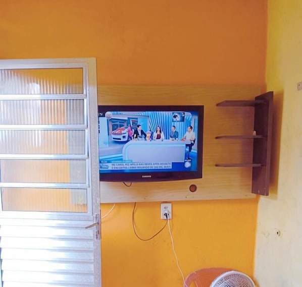 A television mounted on a wall with a wooden shelf below it. - Hostel Bryan Tatuape (São Paulo)