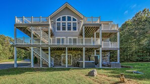 A two-story house with a covered patio, stone foundation, and a hot tub. - 5BR and 5.5 BA Lakefront Home w/private hot tub and dogs ok! (Bumpass)
