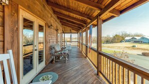 A wooden porch with a covered area, wooden railings, and a view of a residential area. - Dog-friendly, lake view cabin w/ furnished decks, Ping-Pong & darts (Mineral)