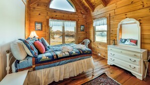 A wooden cabin bedroom with a bed, dresser, and large windows. - Dog-friendly, lake view cabin w/ furnished decks, Ping-Pong & darts (Mineral)