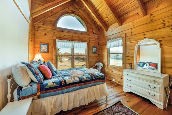 A wooden cabin bedroom with a bed, dresser, and large windows. - Dog-friendly, lake view cabin w/ furnished decks, Ping-Pong & darts (Mineral)