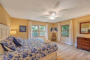 A bedroom with a bed, a dresser, a chair, and a ceiling fan.