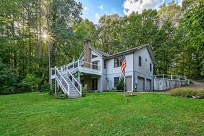 A two-story house with a front porch, a staircase, and a flag.