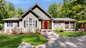 A single-story house with a red front door, a front porch, and a driveway leading to the entrance.