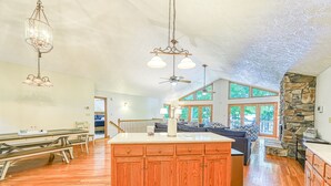Una cocina amplia con armarios de madera, una isla grande e iluminación colgante.