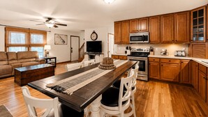 Une cuisine moderne avec des meubles en bois, un four à micro-ondes, une cuisinière et un coin repas comprenant une longue table et des chaises.