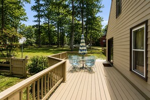 Une terrasse avec une table et des chaises, une clôture en bois et une maison en arrière-plan.