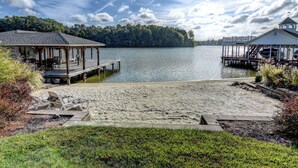 A lakeside dock with a covered seating area and a small building with a tower.