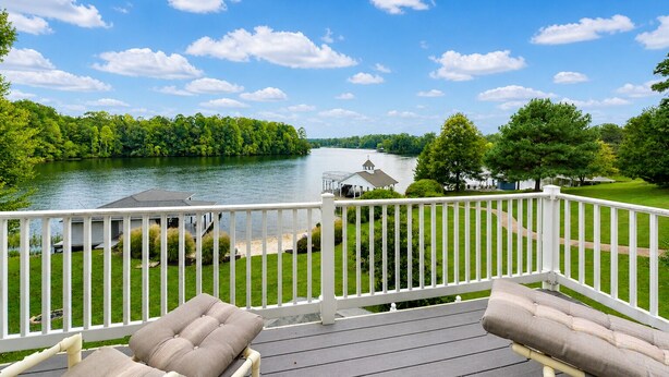 A deck with a view of a lake, a gazebo, and a grassy area.