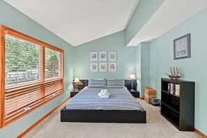 A bedroom with a bed, a window with blinds, a bookshelf, and framed pictures on the wall. - Lakefront retreat with views, hot tub, kid's play area, dock & fiber internet (Mineral)