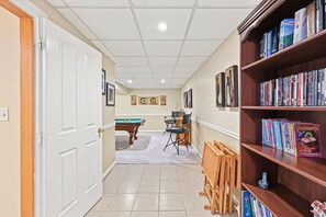 A hallway with a pool table, chairs, and a bookshelf filled with books. - Lakefront retreat with views, hot tub, kid's play area, dock & fiber internet (Mineral)
