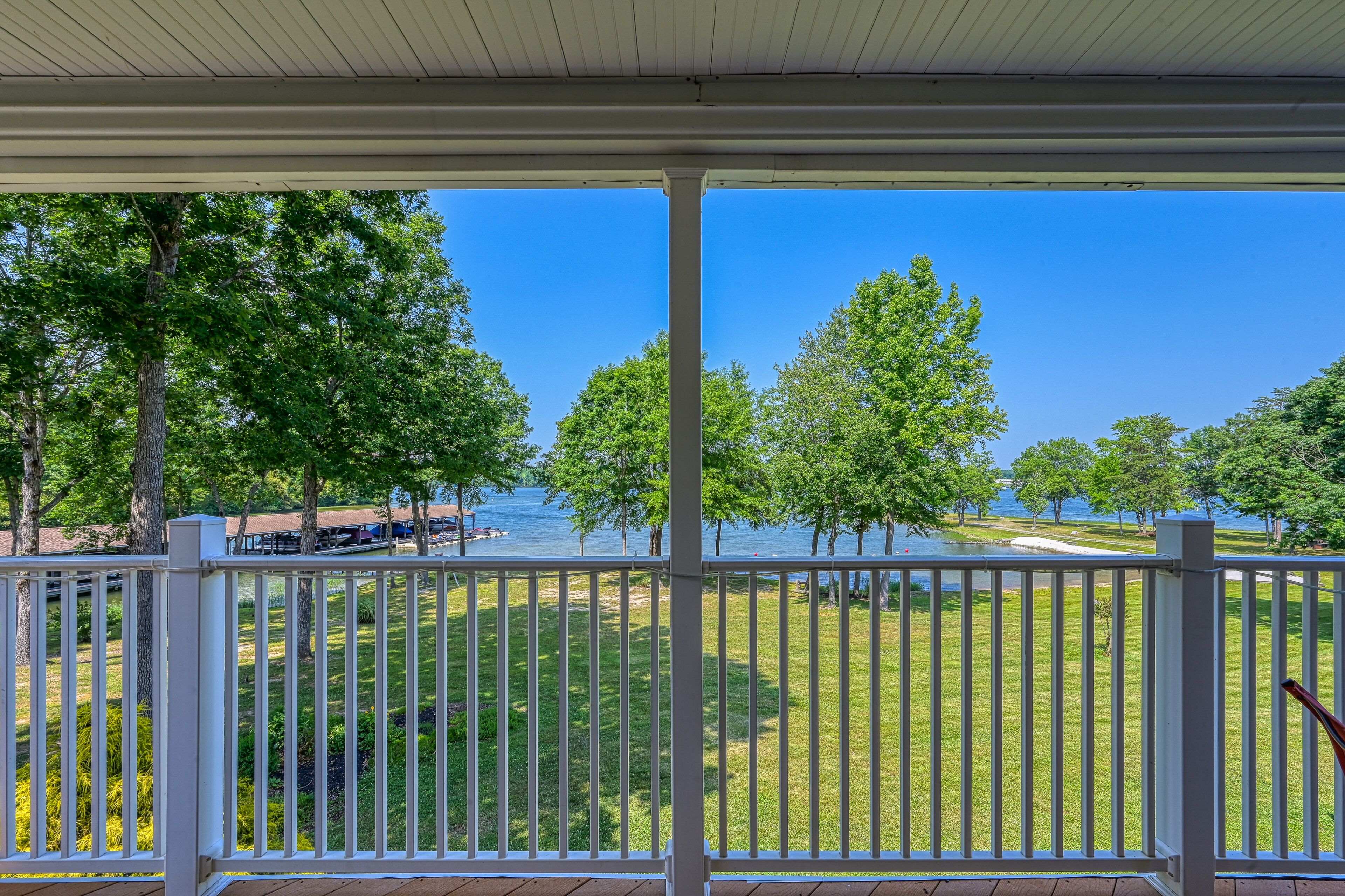 A covered porch with a view of a grassy area and trees.