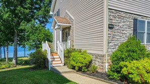A house with a stone facade, a wooden porch, and a view of the water. - Beautiful waterfront townhouse w/ perfect location, fireplace & WiFi (Mineral)