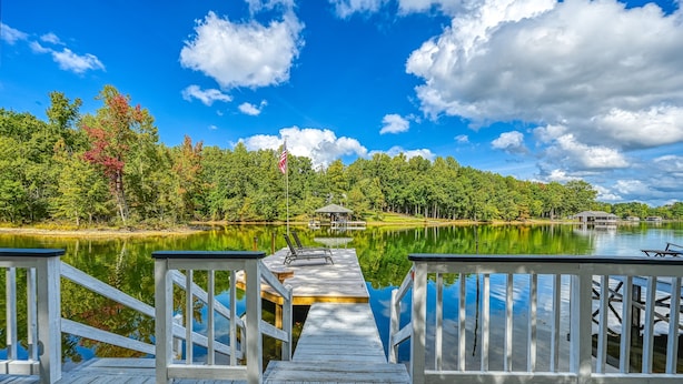 A wooden dock extending into a calm lake, surrounded by trees and a clear sky. - Stunning lakeside home with dock, large deck, kayaks, firepit, & pool table (Bumpass)