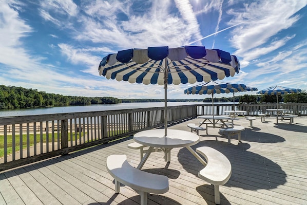 A deck with picnic tables and umbrellas overlooking a body of water.