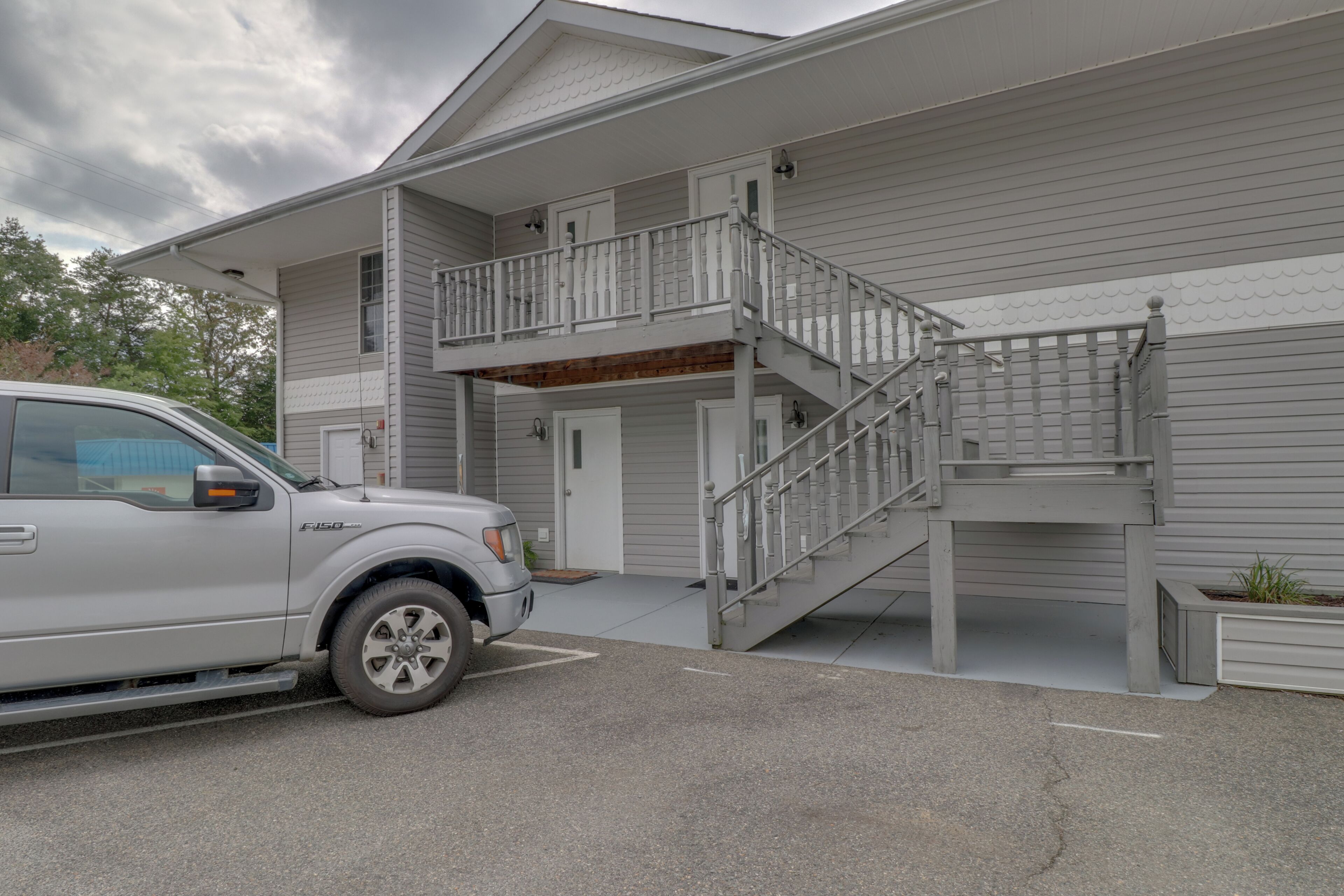 A two-story building with a covered front porch and a staircase leading to the upper level.
