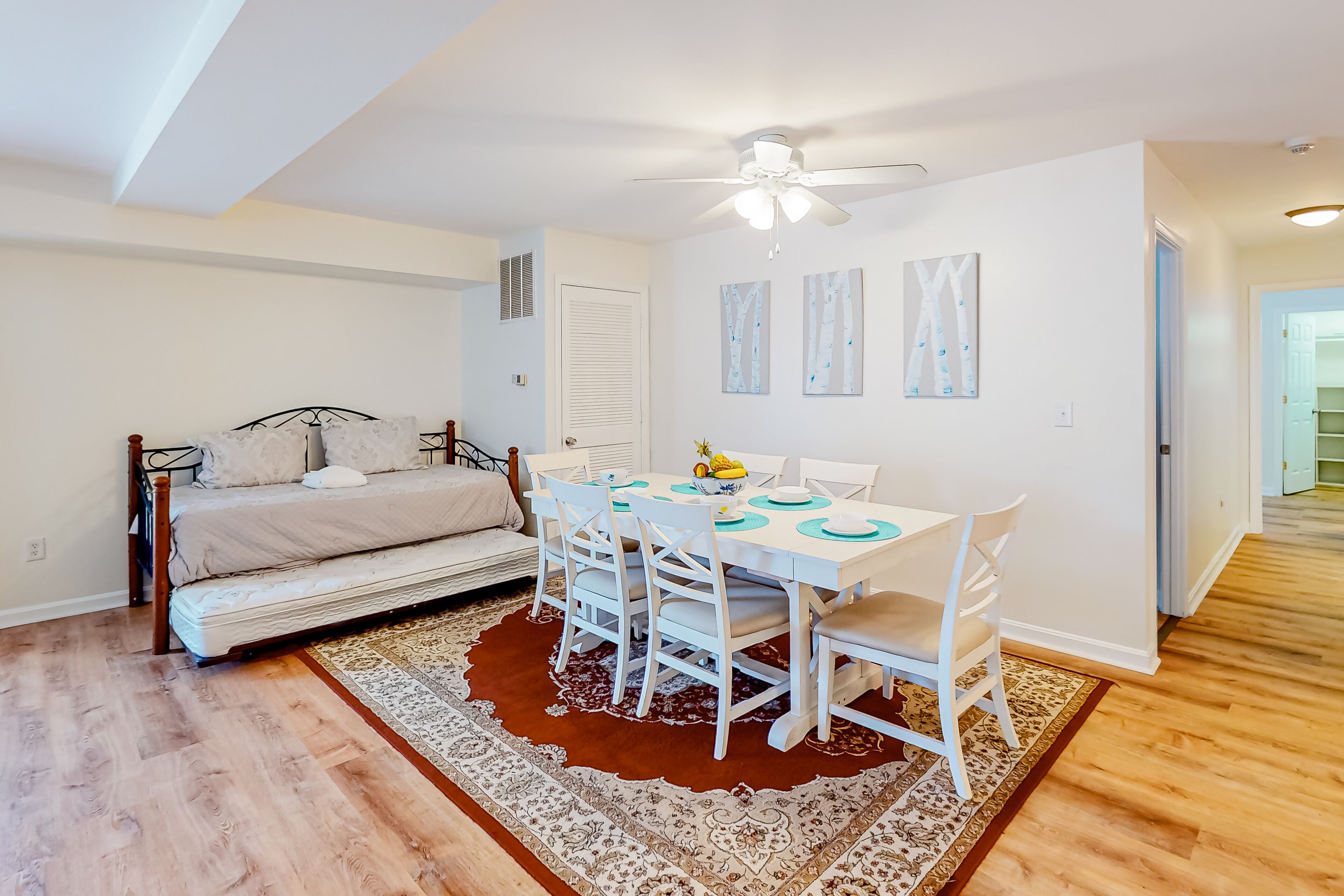 A compact living space with a dining area, a bed, and a ceiling fan.
