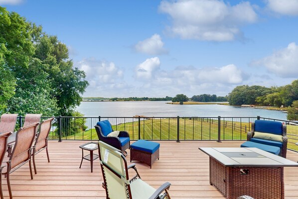 Una terraza con mobiliario exterior, una chimenea y vistas a un lago.