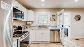 A modern kitchen with white cabinets, stainless steel appliances, and a granite countertop. - Lakefront, dog-friendly home with dock, paddleboards & firepit (Mineral)