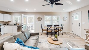 A spacious living area with a leather sofa, a coffee table, and a dining table with chairs. - Lakefront, dog-friendly home with dock, paddleboards & firepit (Mineral)