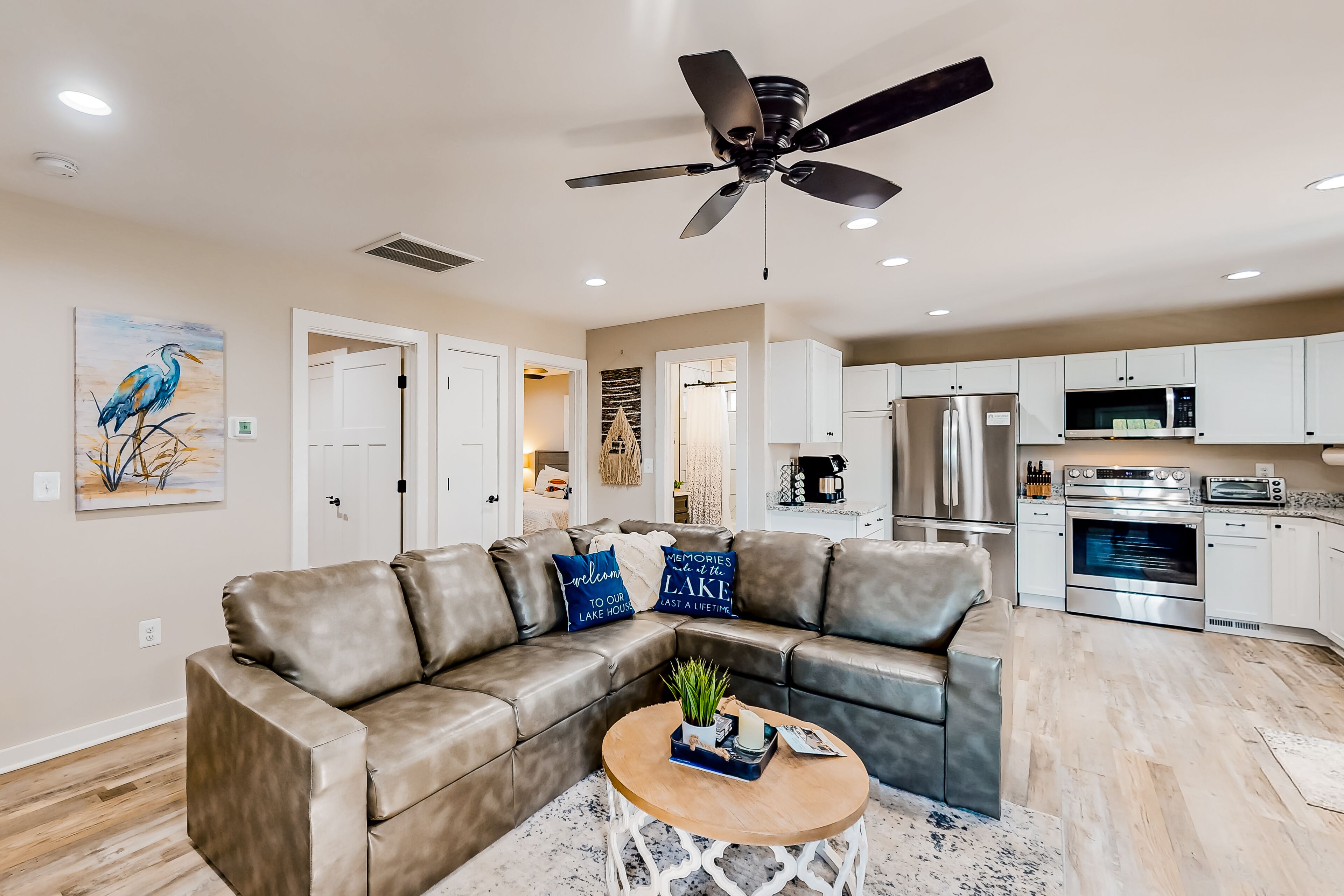 A modern living room with a leather sectional sofa, a round coffee table, and a ceiling fan.