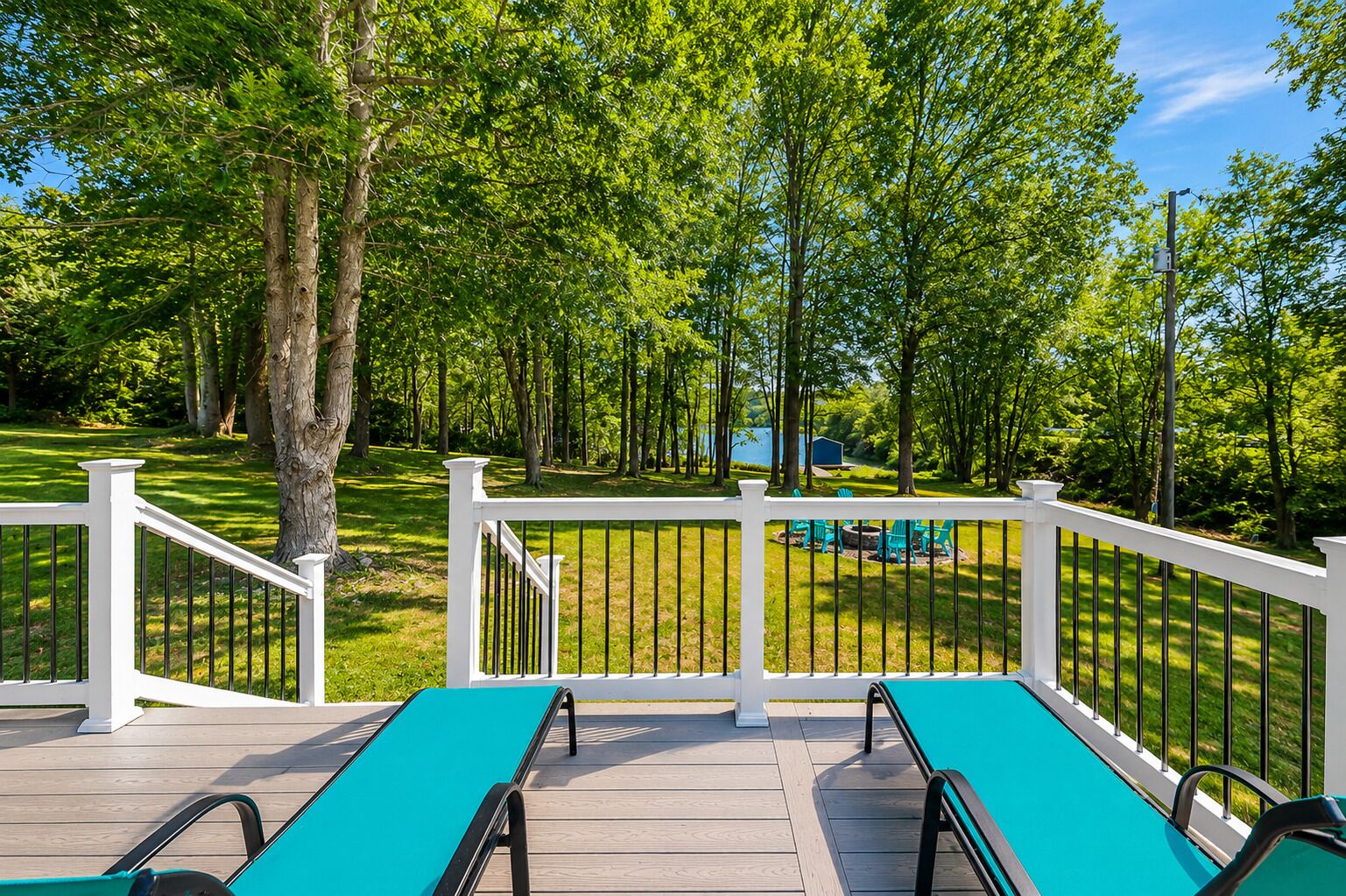 A deck with a pool, surrounded by trees and a grassy area.