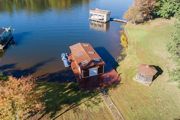 A houseboat with a deck and a small cabin, connected to a dock.