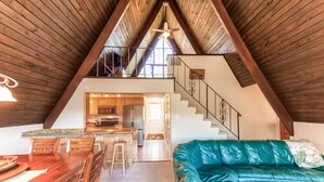 Un espace de vie de style loft comprenant un coin repas, un canapé et un escalier menant à un niveau supérieur.