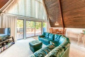Ein geräumiges Wohnzimmer mit einem großen, grünen Ledersofa, einem Flachbildfernseher und einem Bücherregal.