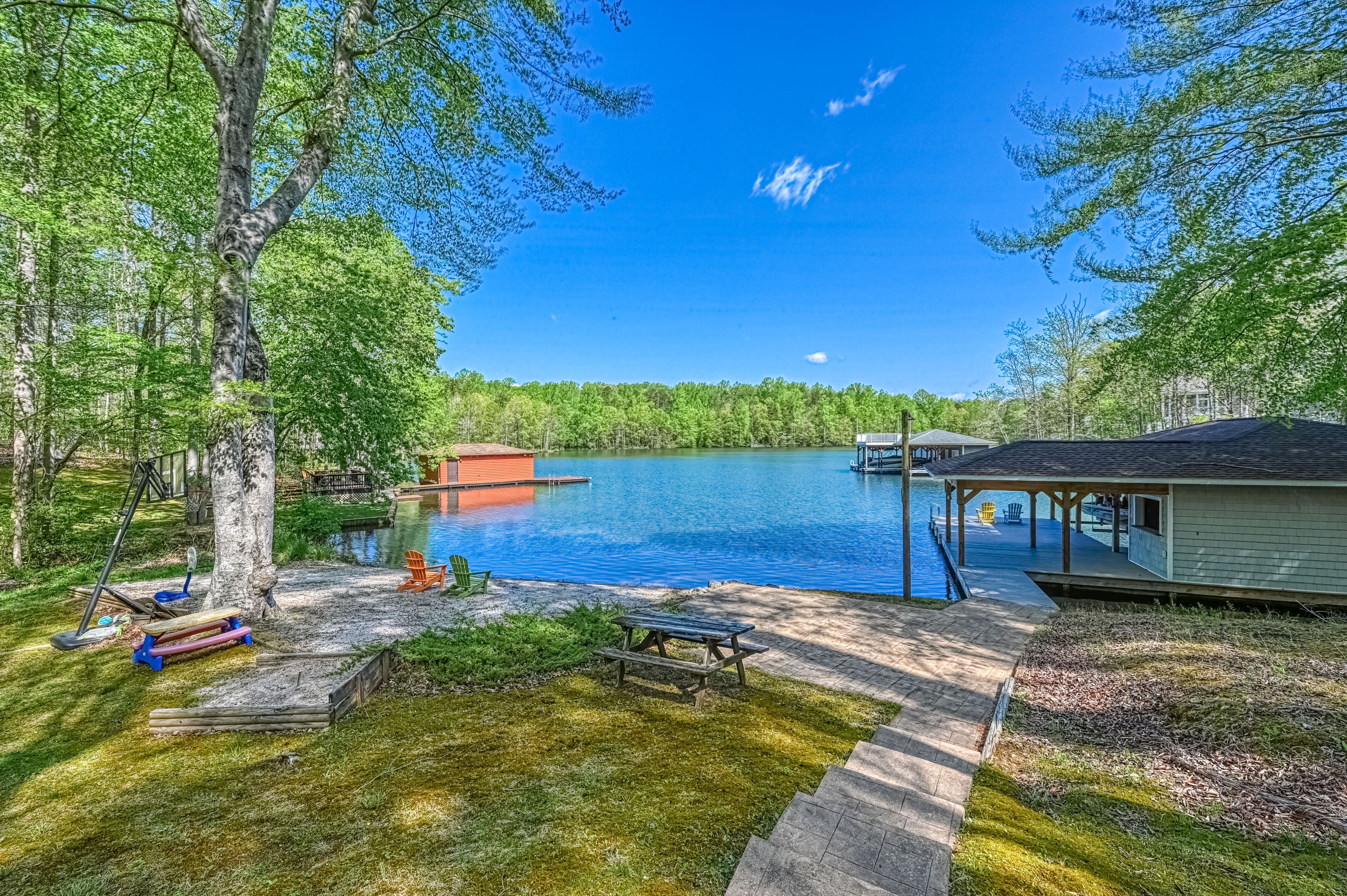 A lakeside property with a dock, picnic table, and outdoor seating area.