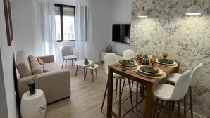 A modern living room with a sofa, dining table, and chairs. - APARTAMENTOS SAN MIGUEL (Jerez de los Caballeros)