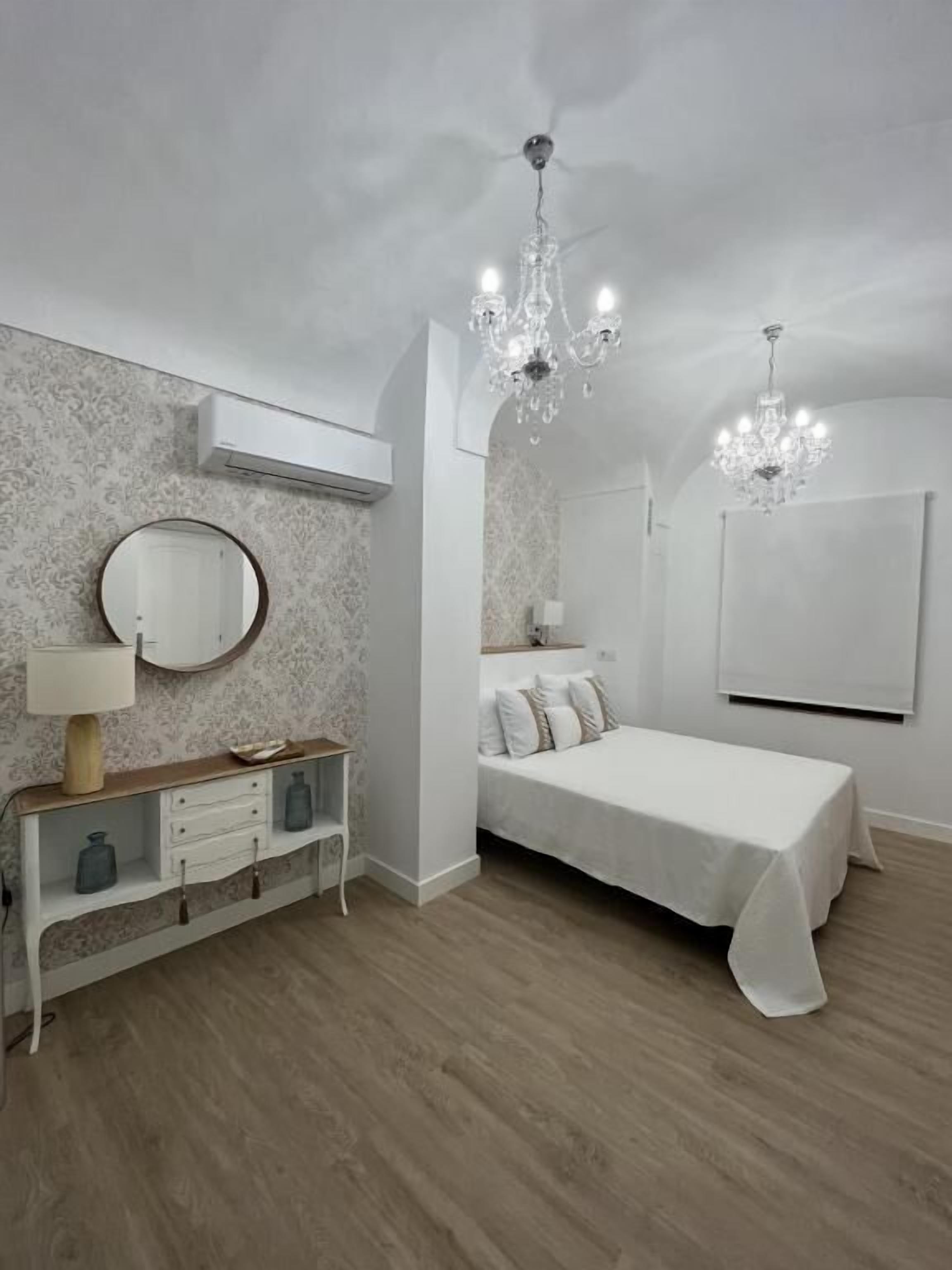 Une chambre à coucher avec un lit, une table de chevet, un miroir et un lustre.