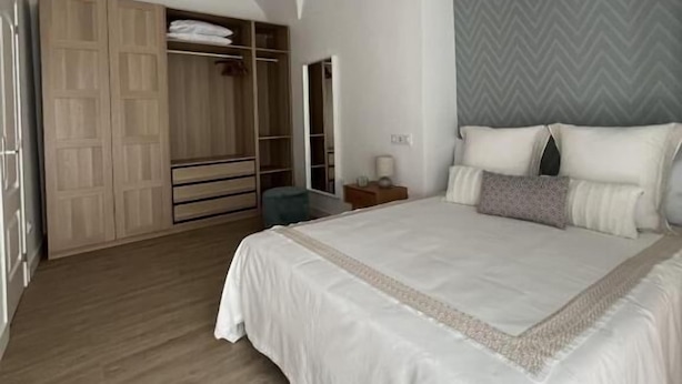 A bedroom with a large bed, a wardrobe, a bedside table, and a hanging light fixture. - APARTAMENTOS SAN MIGUEL (Jerez de los Caballeros)