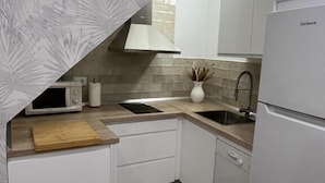 A modern kitchen with white cabinetry, a microwave, a sink, and a refrigerator. - APARTAMENTOS SAN MIGUEL (Jerez de los Caballeros)