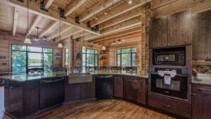A spacious kitchen with wooden cabinets, a large island, and a built-in oven. - Lakefront Cabin w/ Hot Tub, Boat Dock, WiFi, a Game Room & Firepit - Dogs OK (Mineral)