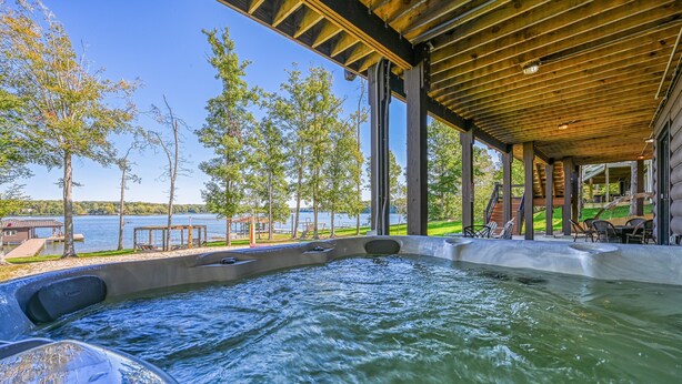 A hot tub area with a view of a lake, wooden deck, and outdoor seating. - Lakefront Cabin w/ Hot Tub, Boat Dock, WiFi, a Game Room & Firepit - Dogs OK (Mineral)