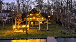 A large house with a porch and a swing set, surrounded by trees and a body of water. - Lakefront Cabin w/ Hot Tub, Boat Dock, WiFi, a Game Room & Firepit - Dogs OK (Mineral)
