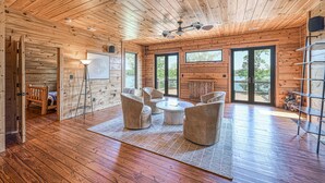 A spacious room with wooden floors, a ceiling fan, and a seating area with a coffee table. - Lakefront Cabin w/ Hot Tub, Boat Dock, WiFi, a Game Room & Firepit - Dogs OK (Mineral)