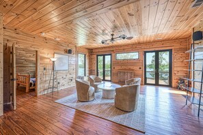 Ein geräumiges Zimmer mit Holzböden, einem Deckenventilator und einer Sitzecke mit Couchtisch.
